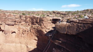 Person stepping off a sandstone ledge on the Moab Rope Swing