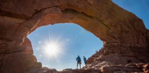 Two men standing inside North Window Arch in Arches National Park