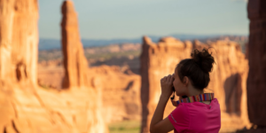 Young girl taking photo at Park Avenue in Arches National Park