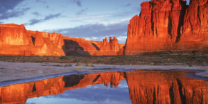 Water-filled pothole reflecting Courthouse Towers at sunset