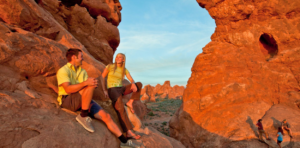 Couple sitting near North Window Arch at sunset