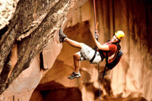 Smiling guest rappelling in Moab sandstone canyon