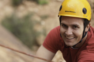 Rock climber descending via controlled rappel in Moab Utah