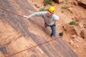 Guided rock climber halfway up sandstone wall in Moab Utah