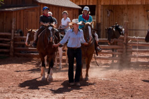 Wrangler leading riders on horses inside training pen before Moab trail ride