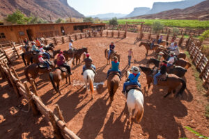 Riders on horses listening to wrangler instruction inside Moab riding arena