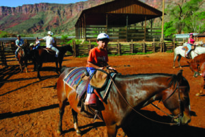 Young rider learning horseback riding basics in ranch arena near Moab