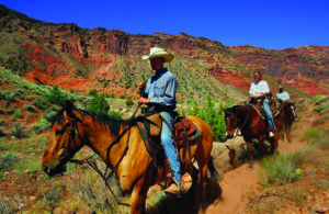 Wrangler leading horseback riders through red rock canyon near Moab