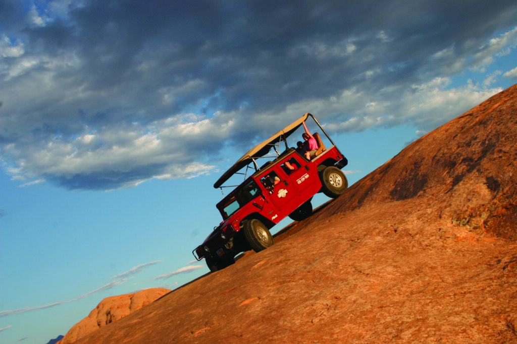 Hummer descending steep slickrock dune on Hell’s Revenge at sunset