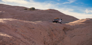 Hummer climbing narrow slickrock ridge on Hell’s Revenge trail