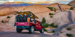 Guests raising hands while riding Hummer over Hell’s Revenge hills