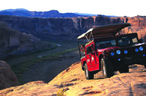 Hummer climbing rocky terrain overlooking Colorado River near Moab